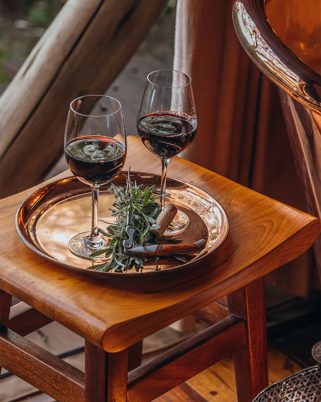 Two glasses of wine resting on a tray beside a window